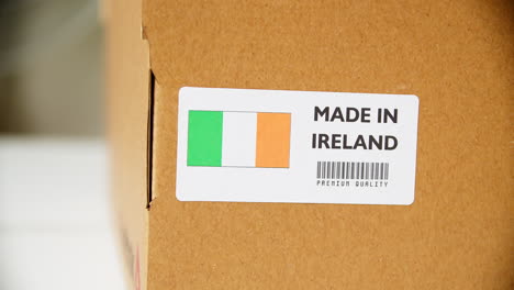 hands applying made in ireland flag label on a shipping cardboard box with products