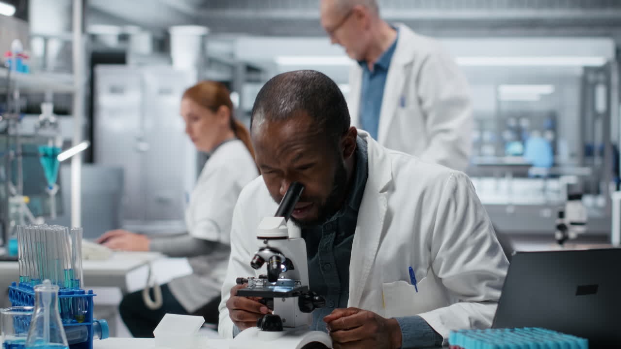 Specialista nello sviluppo di saggi in laboratorio medico che utilizza un microscopio scientifico