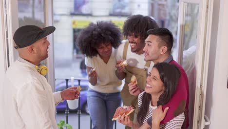 friends socializing and eating pizza on a balcony