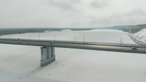 cars drive along large modern bridge over frozen river