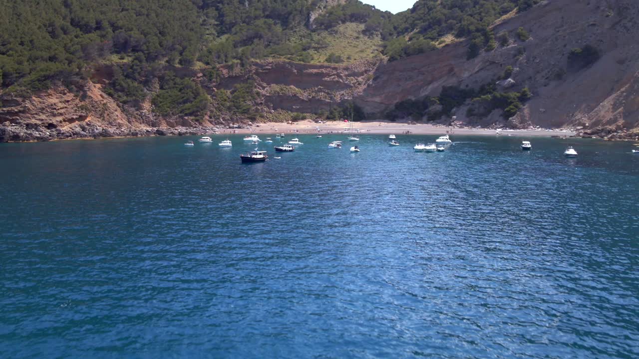 Experience the serene waters and picturesque landscape of Coll Baix, Puerto de Alcudia. Explore the tranquil beach, surrounding hills, and charming boats dotting the bay.