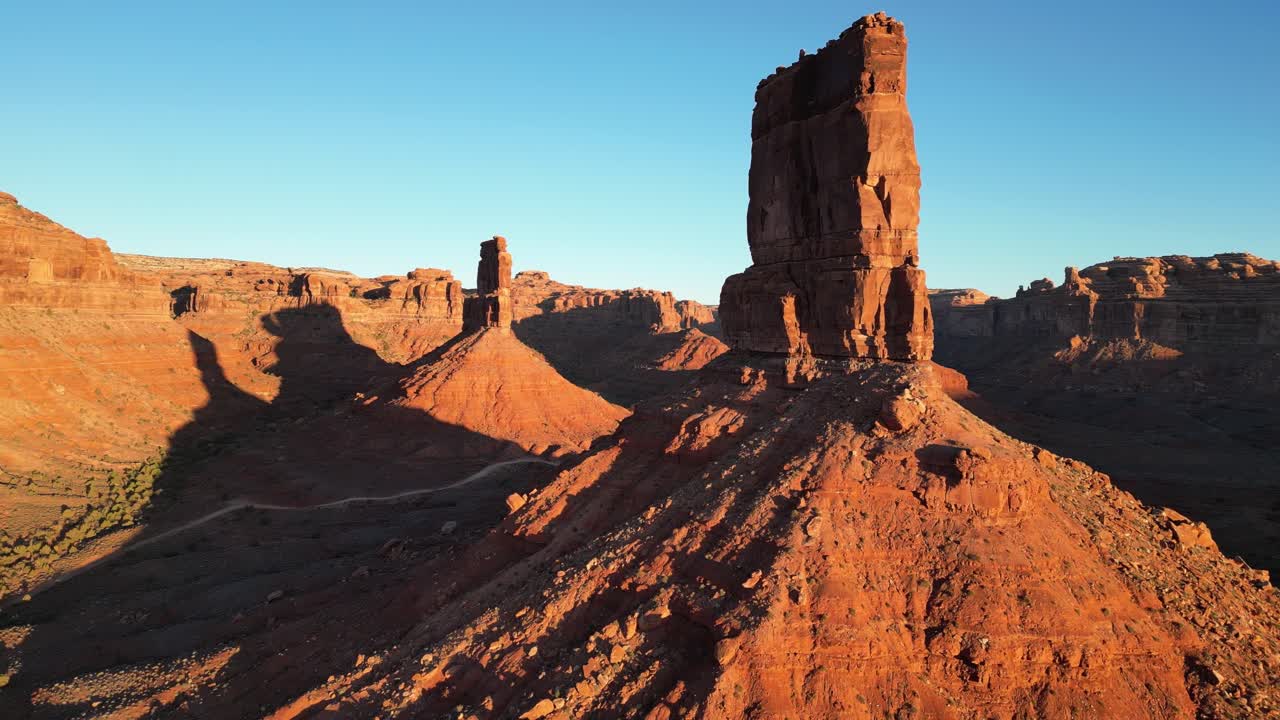 Ripresa aerea in allontanamento che inizia vicino a Castle Butte nella Valley of the Gods, Utah, USA. La camera si allontana da una strada tra le formazioni rocciose, mostrando il vasto deserto con Cedar Mesa in lontananza
