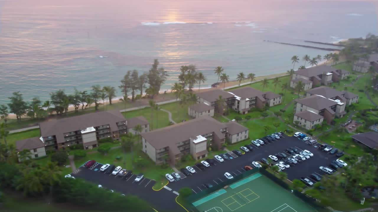 Beautiful Pono kai resort beachfront vacation rental resort in Kapaa Kauai Hawaii at the time of morning sunrise with beautiful clouds and turquoise blue water.