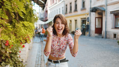 young woman shouting, celebrating success winning goal achievement good victory news in city street