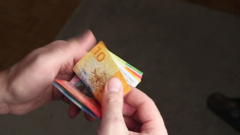 swiss francs cash banknotes being counted by caucasian male hands. close up studio shot, real time, unrecognizable