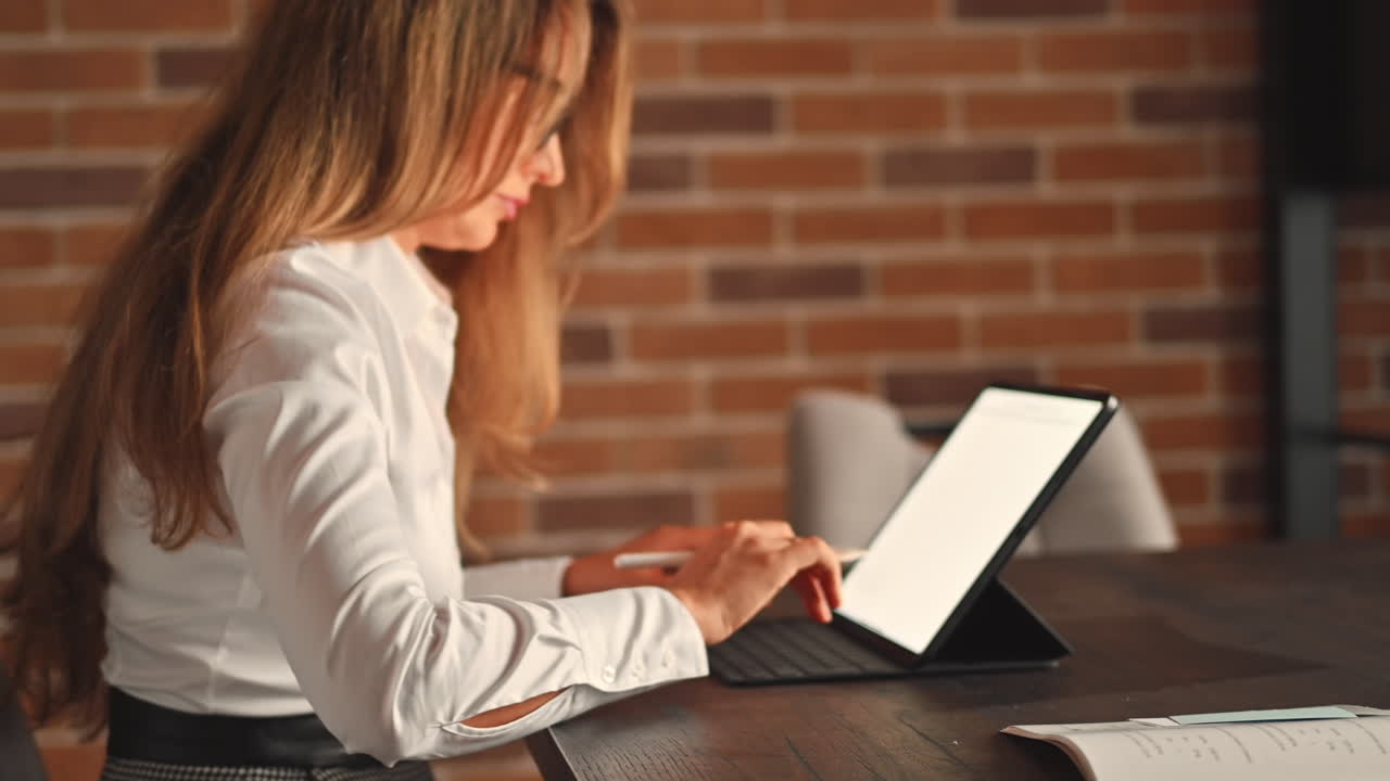 Woman working on a tablet with a stylus pen at an office