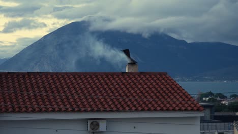 smoke coming out of a chimney rotating rooster of a tiled roof on a cold winter day