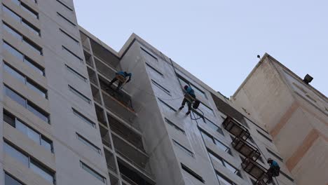 dos trabajadores limpiando ventanas en un edificio alto