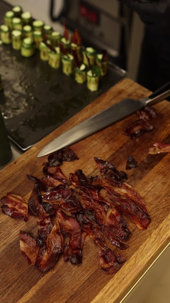 Mano con guanto nero che prende pancetta cotta da un tagliere