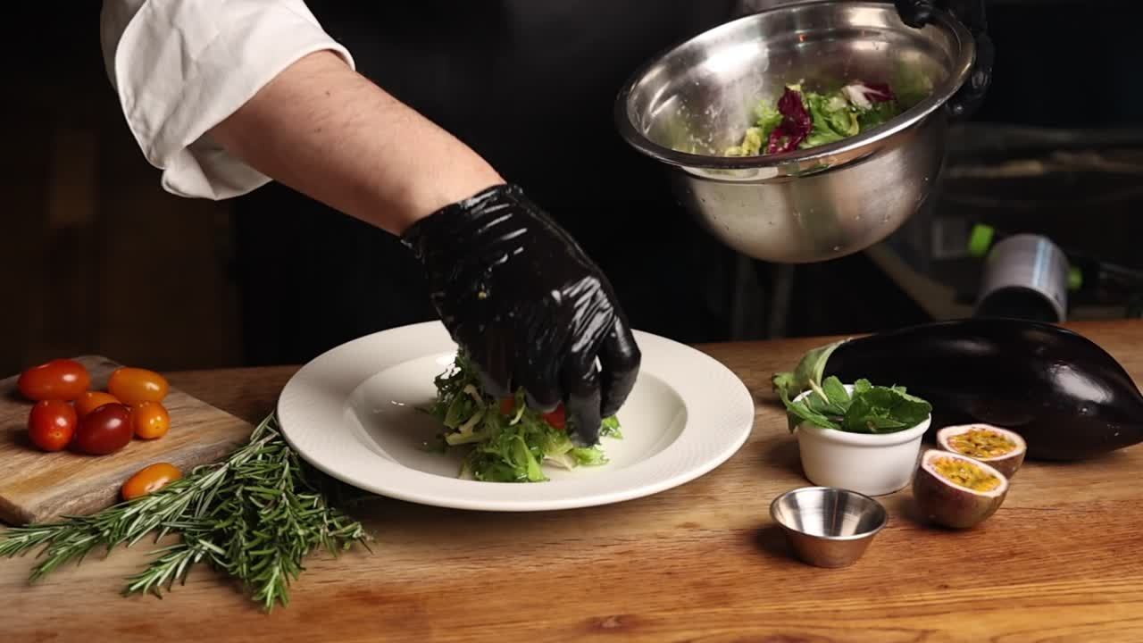 Chef che impiattano insalata verde fresca con verdure in una cucina professionale