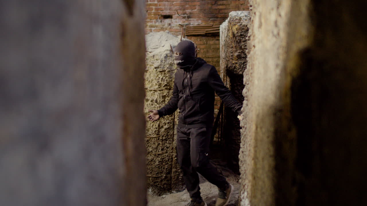 폐허가 된 건물을 걷는 동안 도끼를 들고 검은 옷을 입은 가면을 쓴 남자