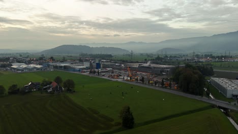 Aerial-approaching-shot-of-Construction-site-at-Chocolate-factory-in-Bilten-with-mountains-in-background