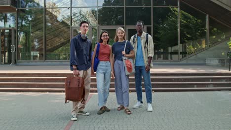 four students posing in front of university building