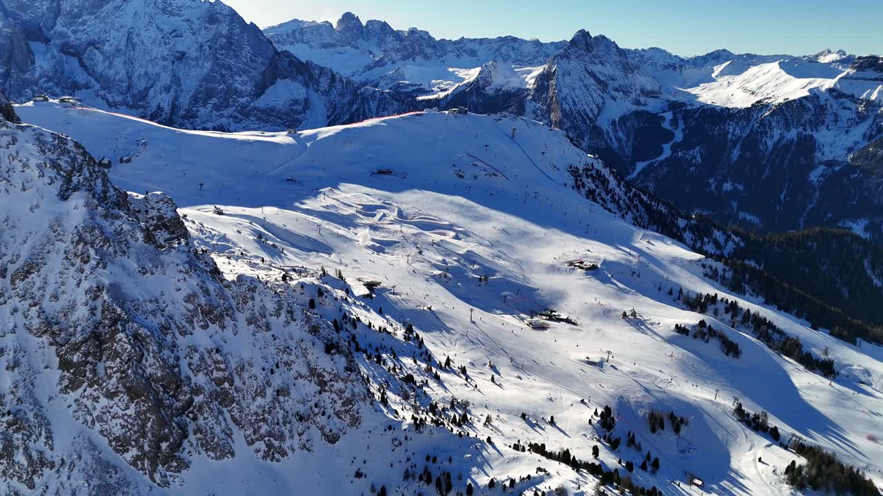 Ski piste in the Italian Dolomites surrounded by mountains during winter season (drone footage)