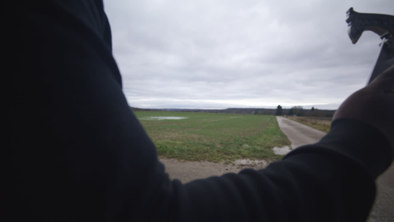 Modern Black Swordsman Warrior Awaiting Battle Opponent in Open Field Under Grey Sky, Europe, 4K | Muscular, Intimidating, Shadow, Figure, Blurry, Dark Clothes, Powerful, Close Up, Arm, Waiting, Hand