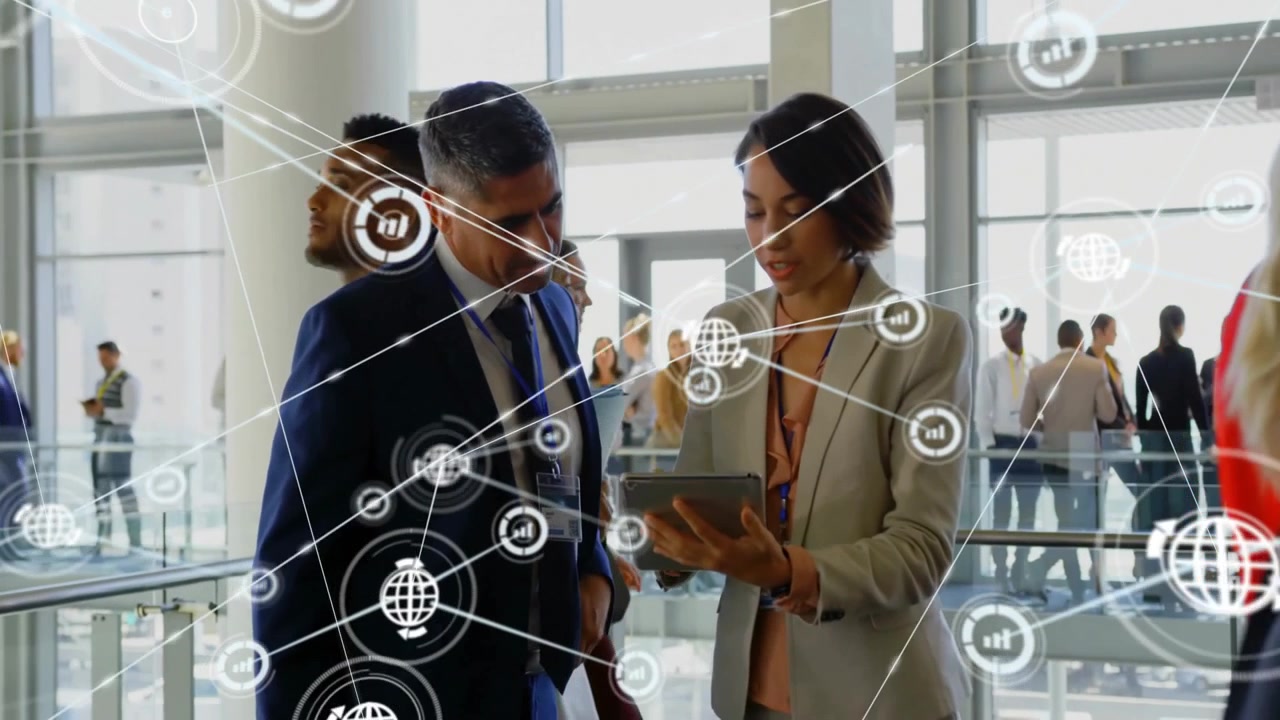 Collègues d'affaires collaborant sur une tablette dans un atrium, présentant des icônes et des lignes de réseau numérique