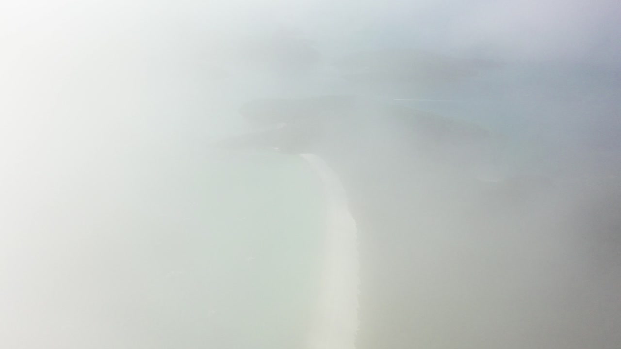 Dawn tourism aerial retreats into thick fog above Whitehaven Beach