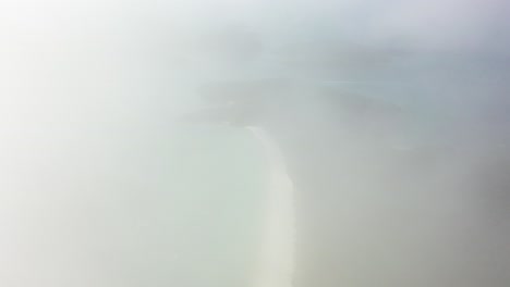 Dawn tourism aerial retreats into thick fog above Whitehaven Beach
