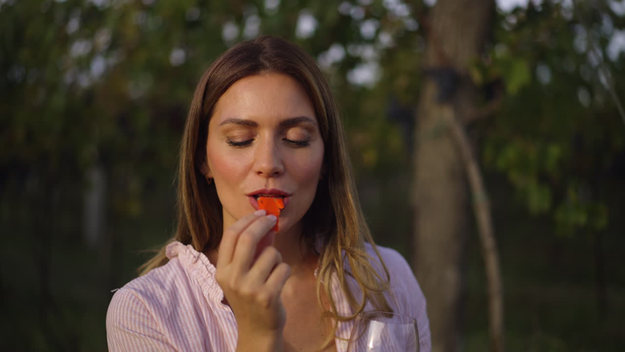 Woman eating strawberry and drinking wine in a vineyard