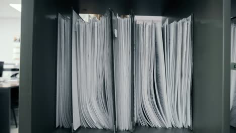 woman in the office takes a folder with documents from the document rack