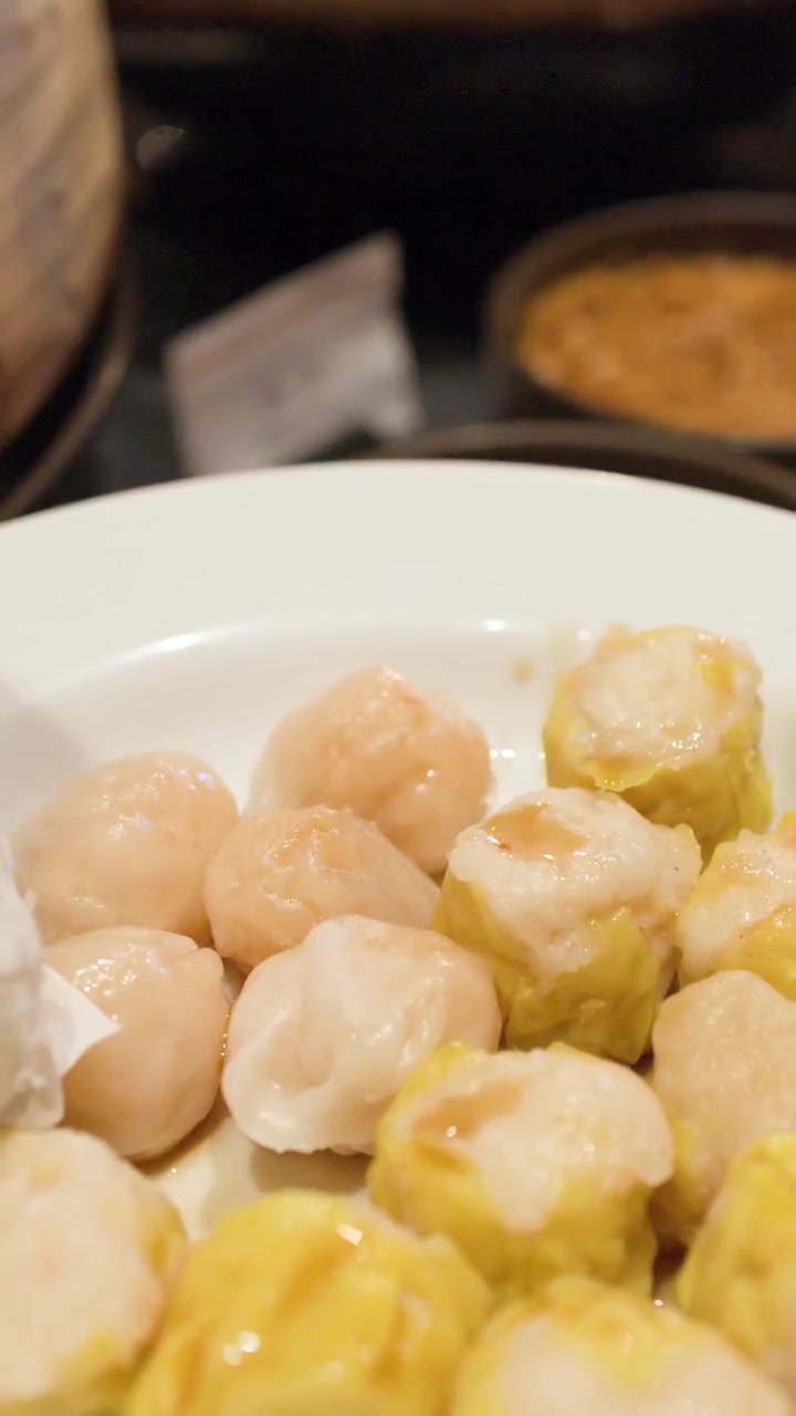Bidikan close-up menunjukkan sendok menuangkan kecap di atas dim sum Cina kukus segar.