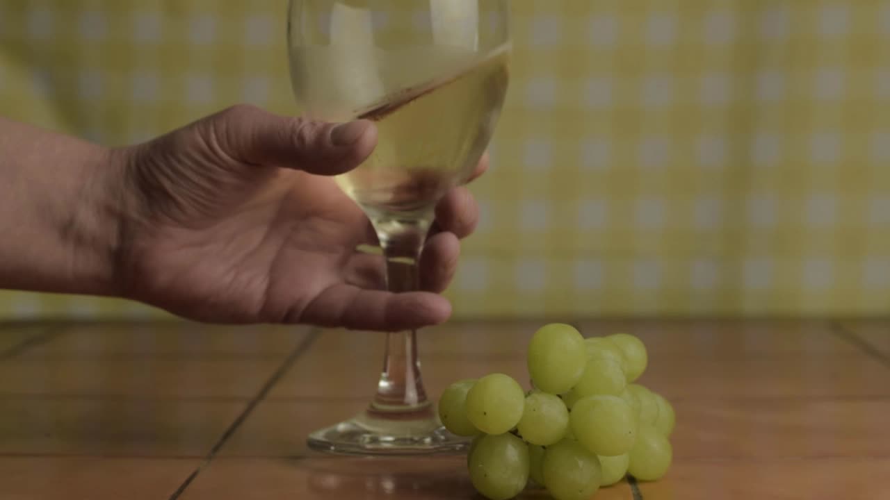 mano con copa de vino blanco y uvas primer plano