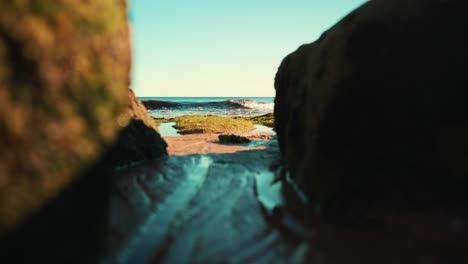 ocean shoreline with gentle waves gently hit sand between rocks at sunset 4k