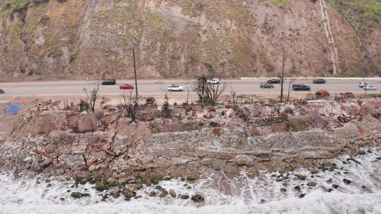 Low dolly aerial shot of beachfront residential lots burned by the Palisades wildfire in Malibu, California. 4K