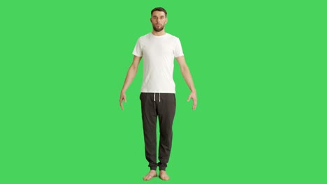 long shot of a bare foot man wearing t-shirt and sweatpants while camera rotates around him. shot on a green screen background.