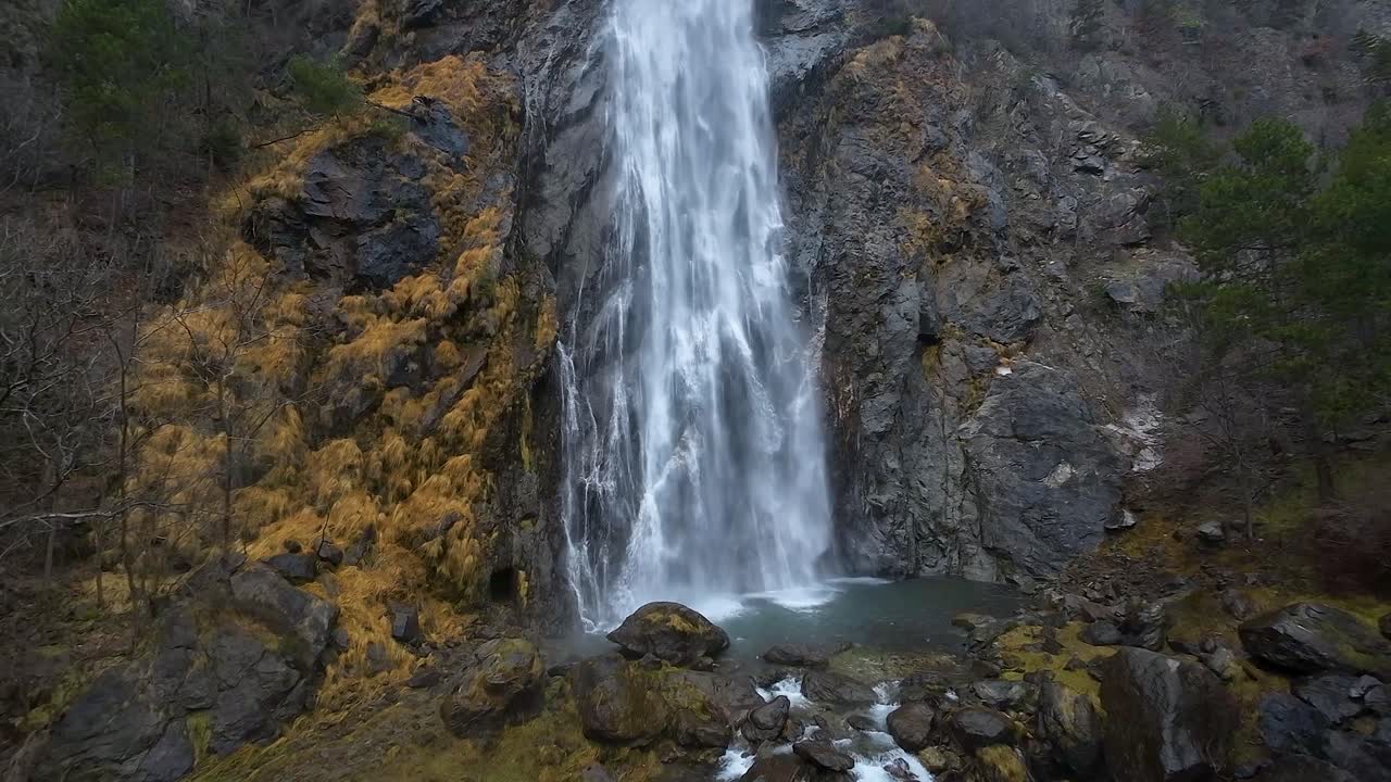 Splendida veduta aerea ravvicinata di una potente cascata che si getta da una scogliera scoscesa in una serena pozza sottostante.