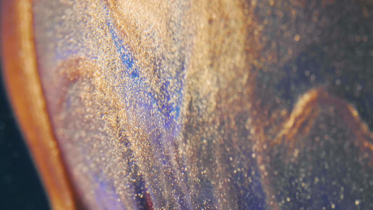 las partículas de tinta dorada fluyen en el agua como un caos colorido en el fondo negro