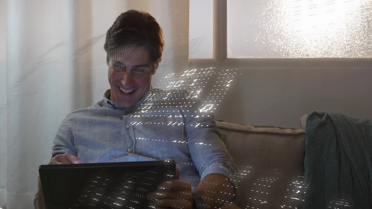 Man tapping tablet on sofa, causing animated binary grid drifting across torso for tech demo