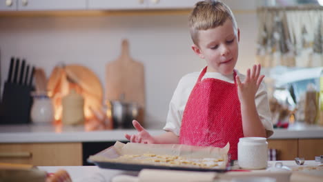 niño lame los dedos mientras hornea pasteles navideños