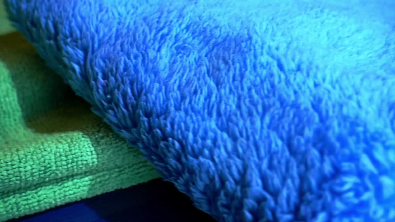Close up left to right sliding shot of various microfiber towels in yellow, green and blue