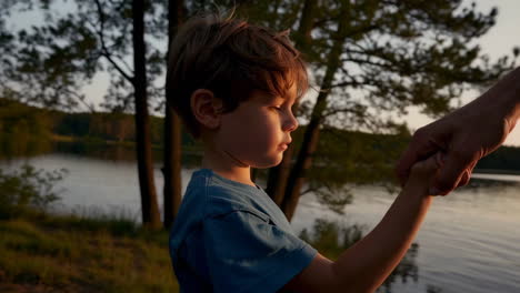 parent and child holding hands by a lake at sunset