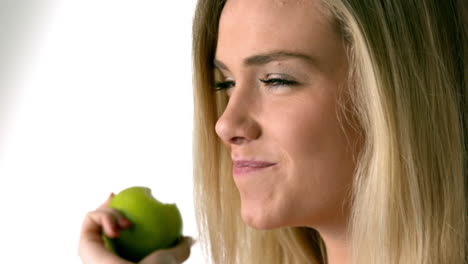 una bonita rubia comiendo una manzana verde