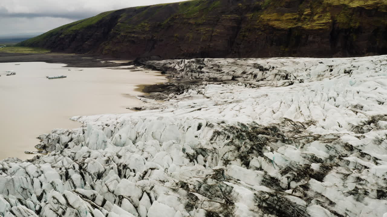 vista de pájaro de una colina y un campo de nieve agrietado en el área de fjallsárlón
