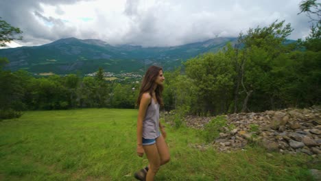 una mujer morena en una caminata caminando por un exuberante prado verde en un claro dentro del bosque en un día nublado