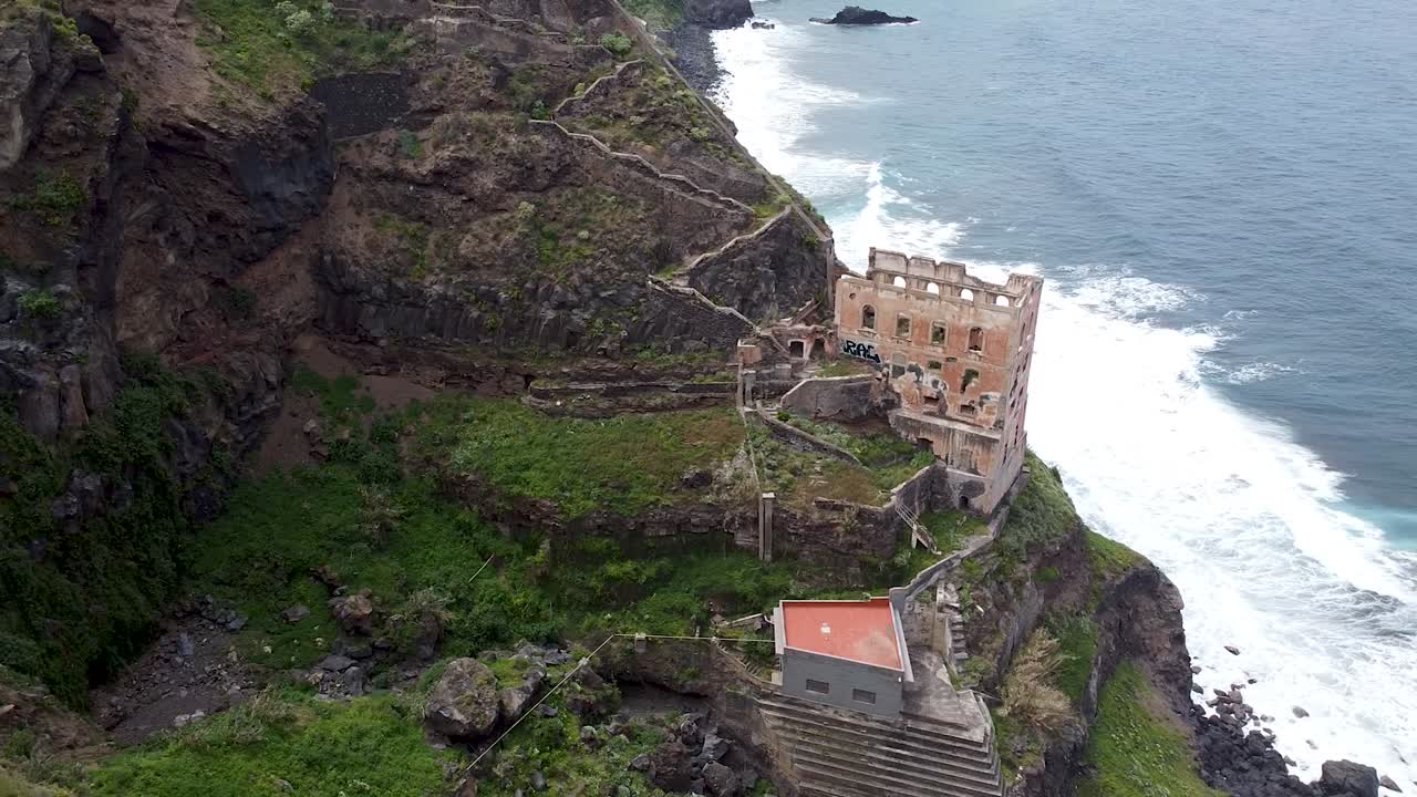 Vista aérea de drone de ruínas de uma casa abandonada junto ao oceano.