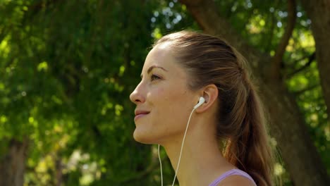 runner drinking water and listening to music in the park