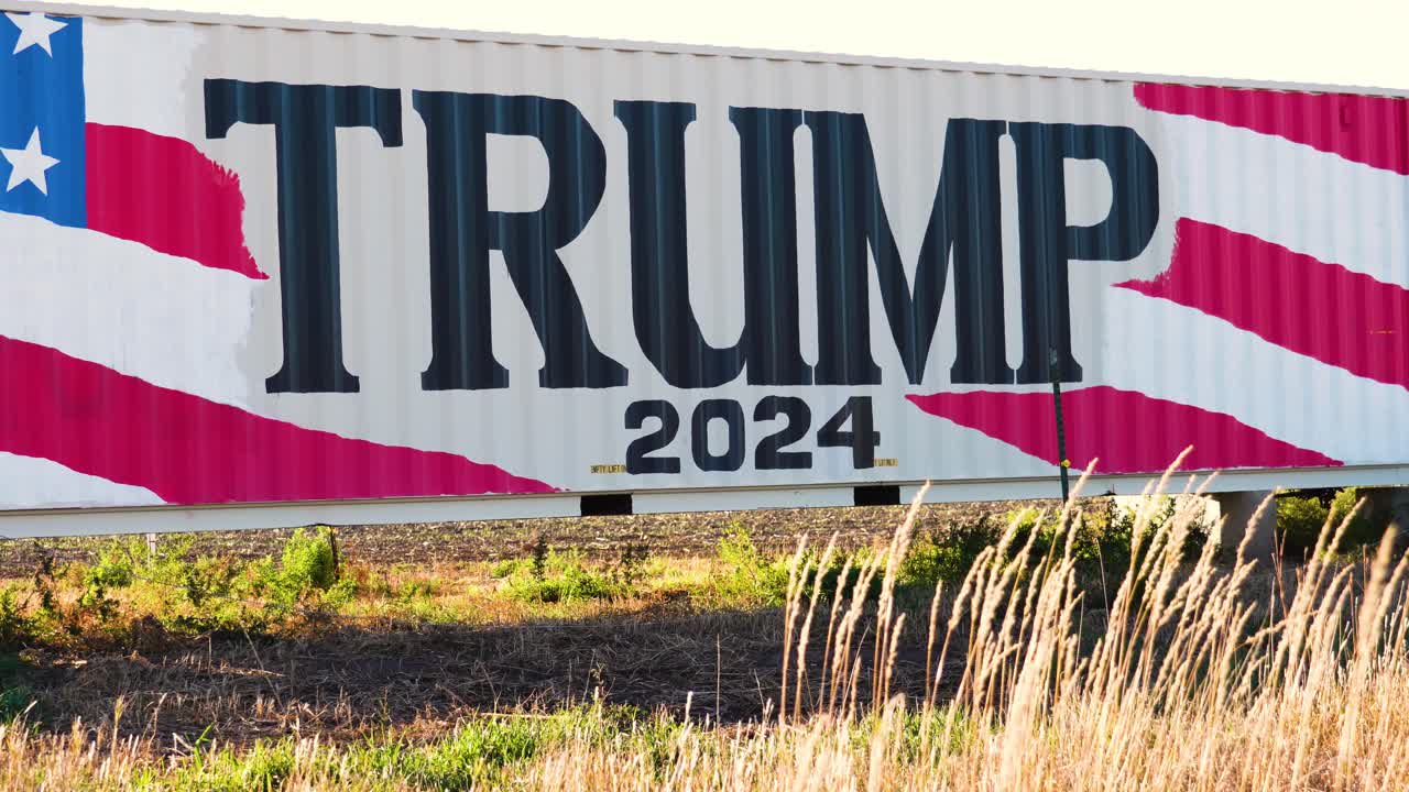 Donald Trump 2024 Presidential Election Campaign Sign Painted on a Large Truck or Trailer in Rural Farm Land with Tall Grass in the Middle of Nowhere
