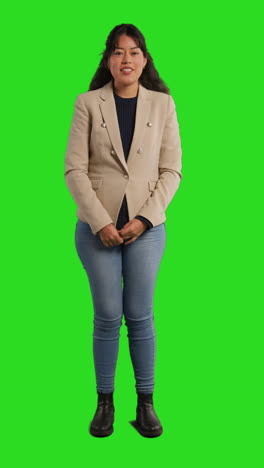 vertical video full length studio shot of female teacher talking to class standing against green screen