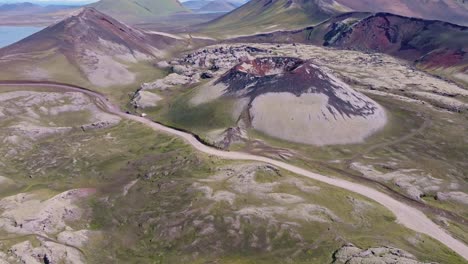 aerial drone view with a bottom-to-top reveal movement, focusing on stutur crater with the landmannalaugar mountains in the background