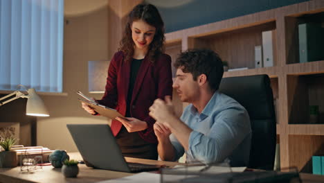 woman secretary bringing coffee cup to tired man boss working late in office.