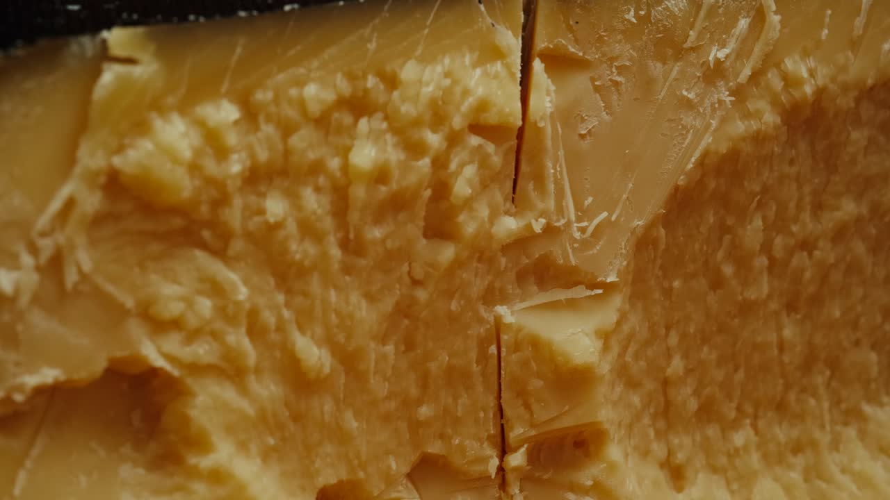Forma di parmigiano di medie dimensioni su tagliere di legno, ripresa in rotazione