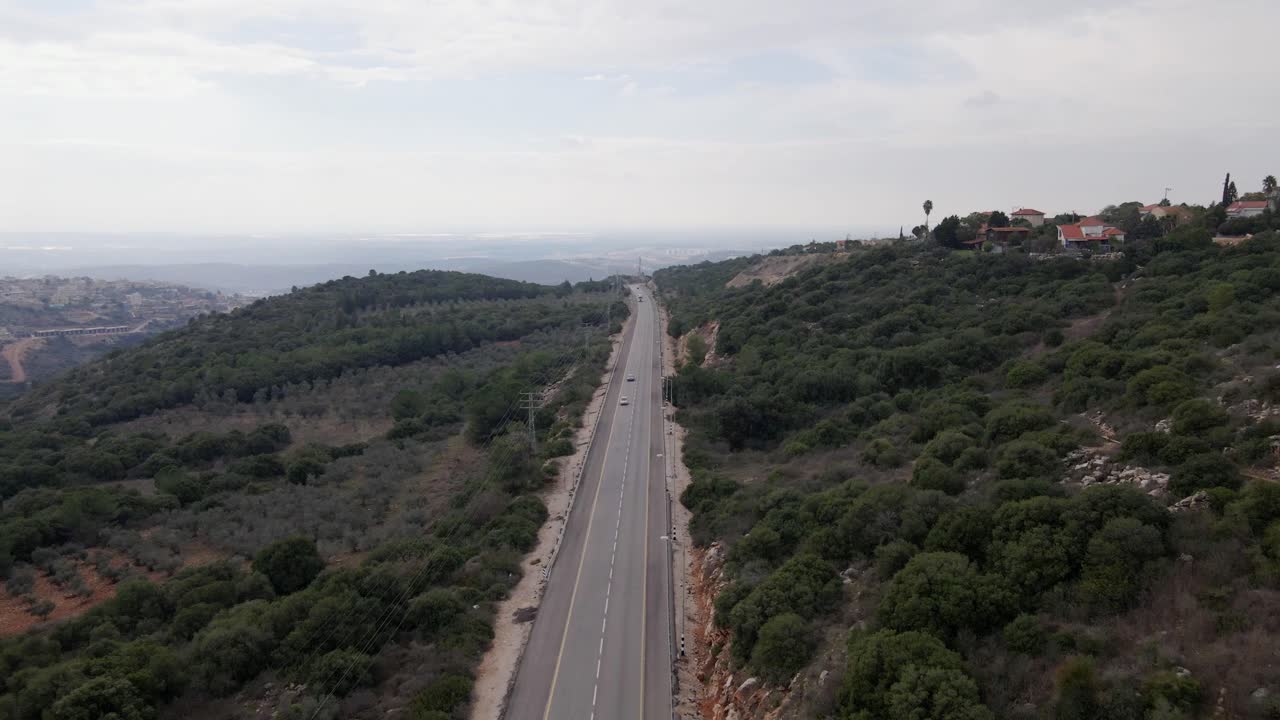 Riprese aeree su una grande autostrada tra le montagne e una pineta. Vista drone su Israele, Katzir.