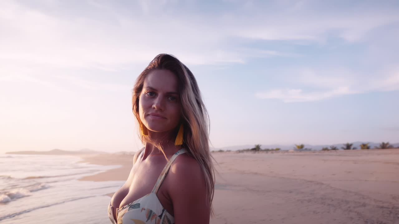 Slow Motion of a woman's bare feet on the beach as a wave approaches at sunset