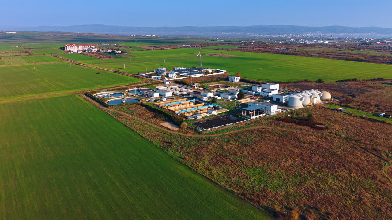 Vast green fields surround the territory of the modern water treatment plant. Drone footage approaching the sewage recycling capacity