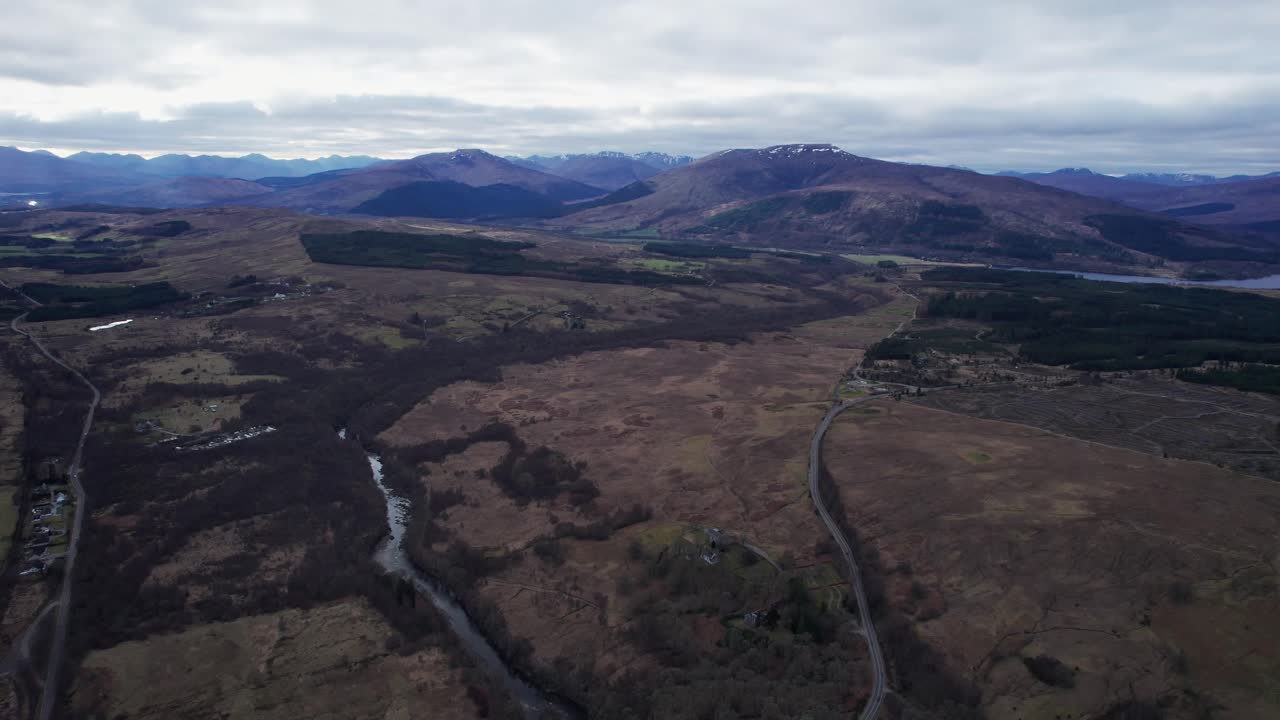 toma panorámica aérea que revela montañas cubiertas de nieve con arroyos en los campos