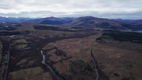 Aerial-panoramic-shot-revealing-snow-capped-mountains-with-streams-in-fields